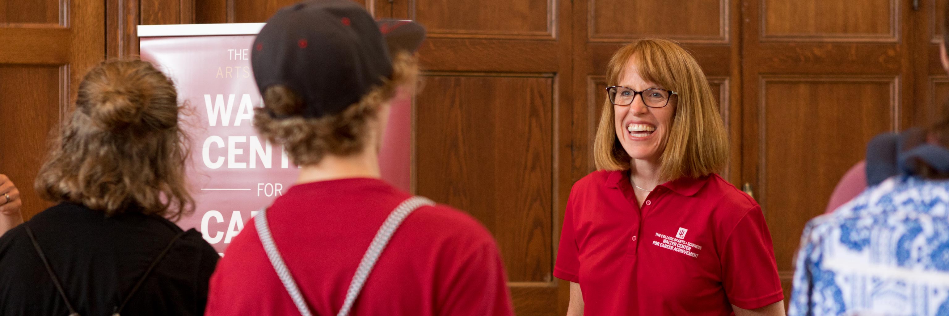 older woman smiling at students during an expo
